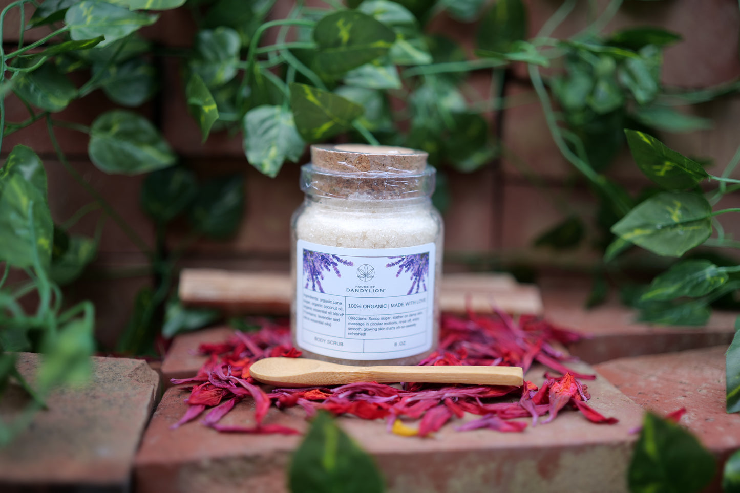 house of dandylion sugar scrub on display in a glass jar with a wooden spoon