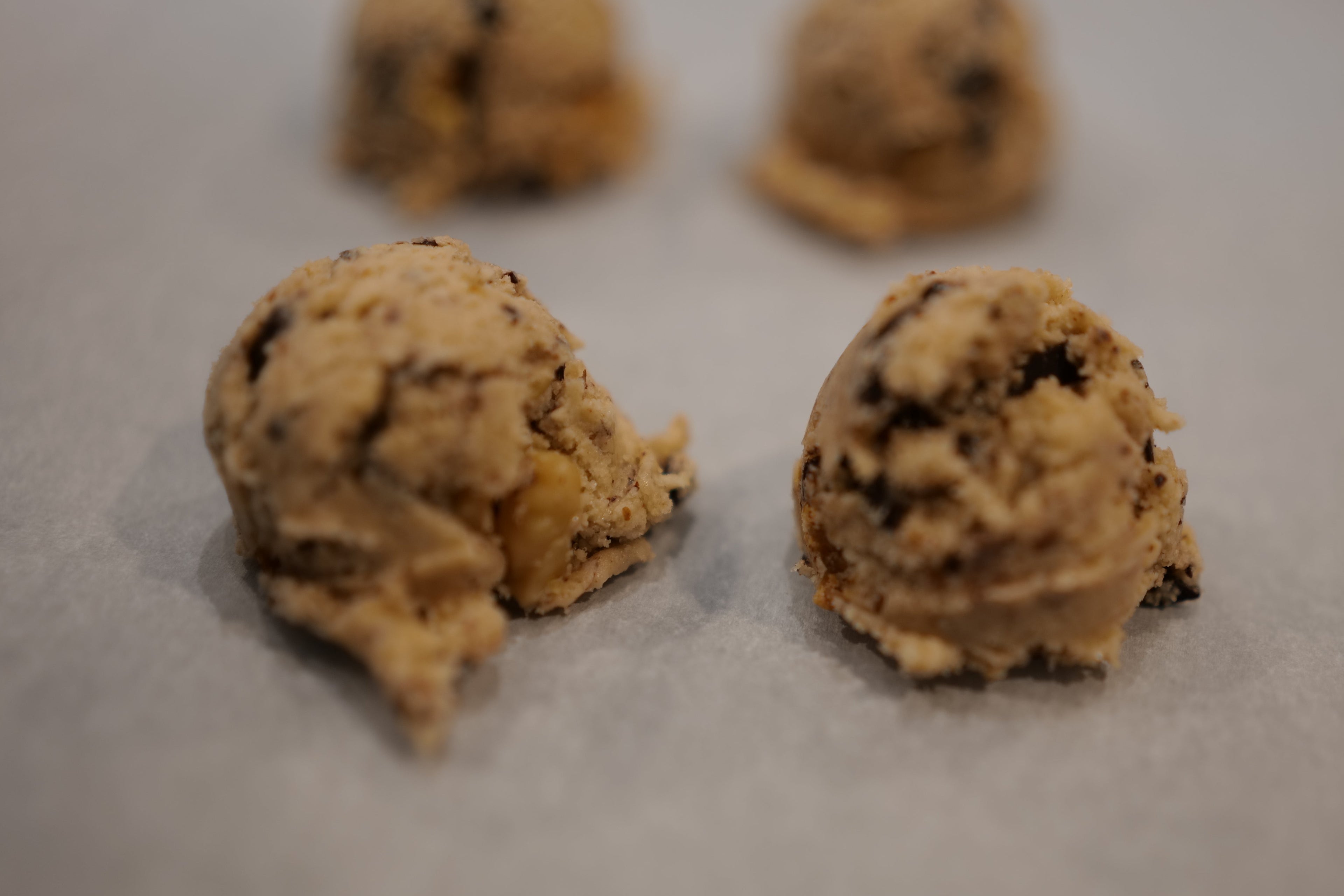choco-walnut Cookie dough balls with chocolate chips on a baking sheet