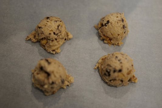Four uncooked cookie dough balls on a baking sheet
